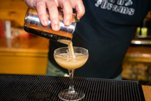 Straining bourbon flip into coupe glass